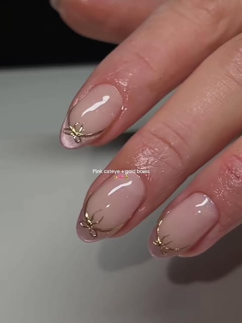 Pink cat-eye nails with hand-set gold bow charms